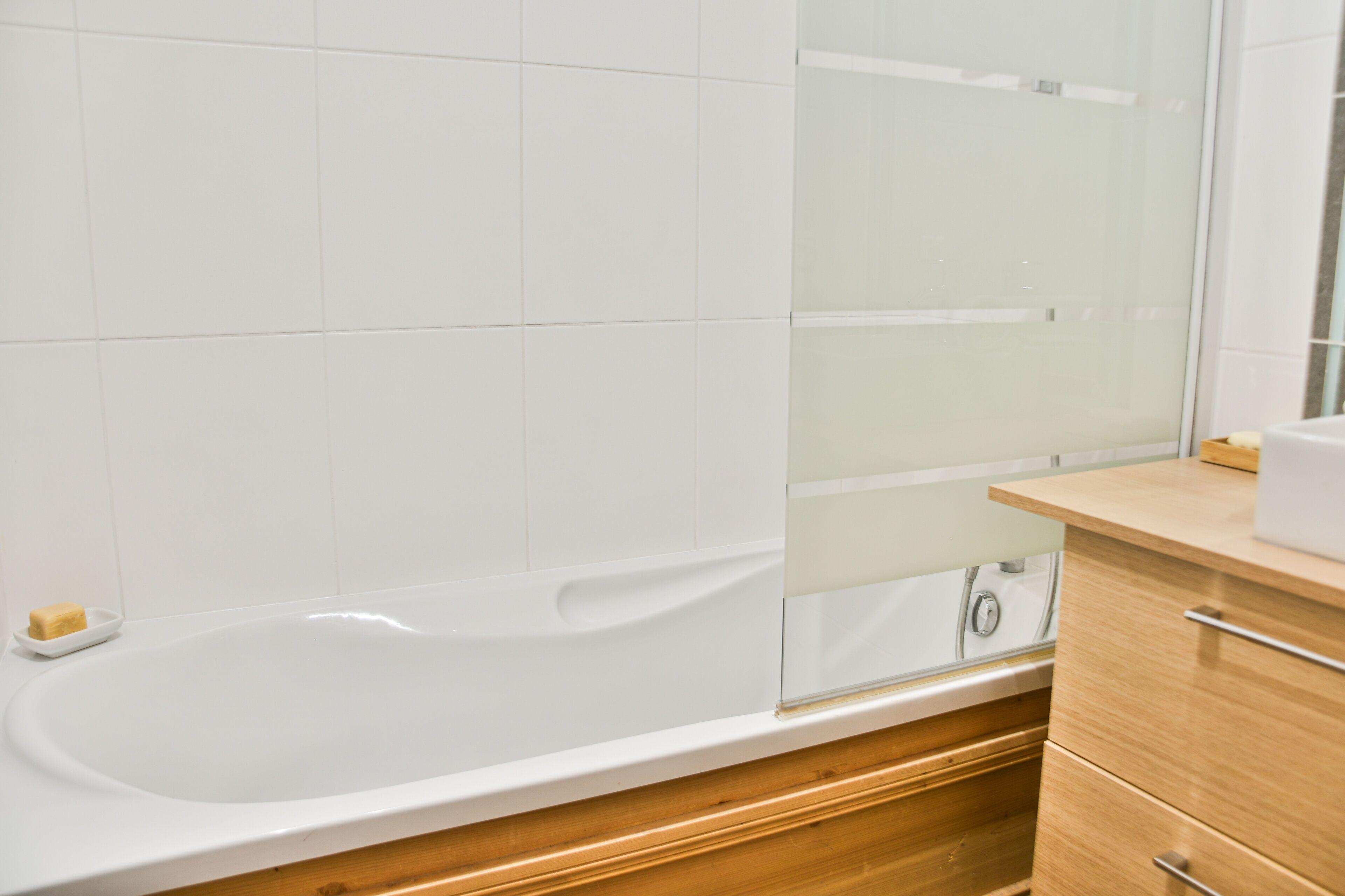 Une salle de bain avec une baignoire blanche, des meubles en bois et une cabine de douche en verre.
