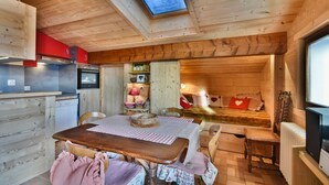 Un interior de cabaña acogedor con una mesa de comedor de madera, sillas, un sofá y una cama.