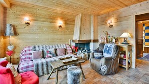 Interior acogedor de una cabaña de madera con sofá, sillón y chimenea.