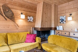 A wooden interior with a sofa, armchair, and fireplace. - Mont Blanc 4 - Three Bedroom Apartment, Sleeps 6 (Le Grand Bornand)