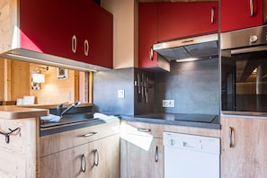 A modern kitchen with wooden cabinets, stainless steel appliances, and a built-in dishwasher. - Mont Blanc 4 - Three Bedroom Apartment, Sleeps 6 (Le Grand Bornand)