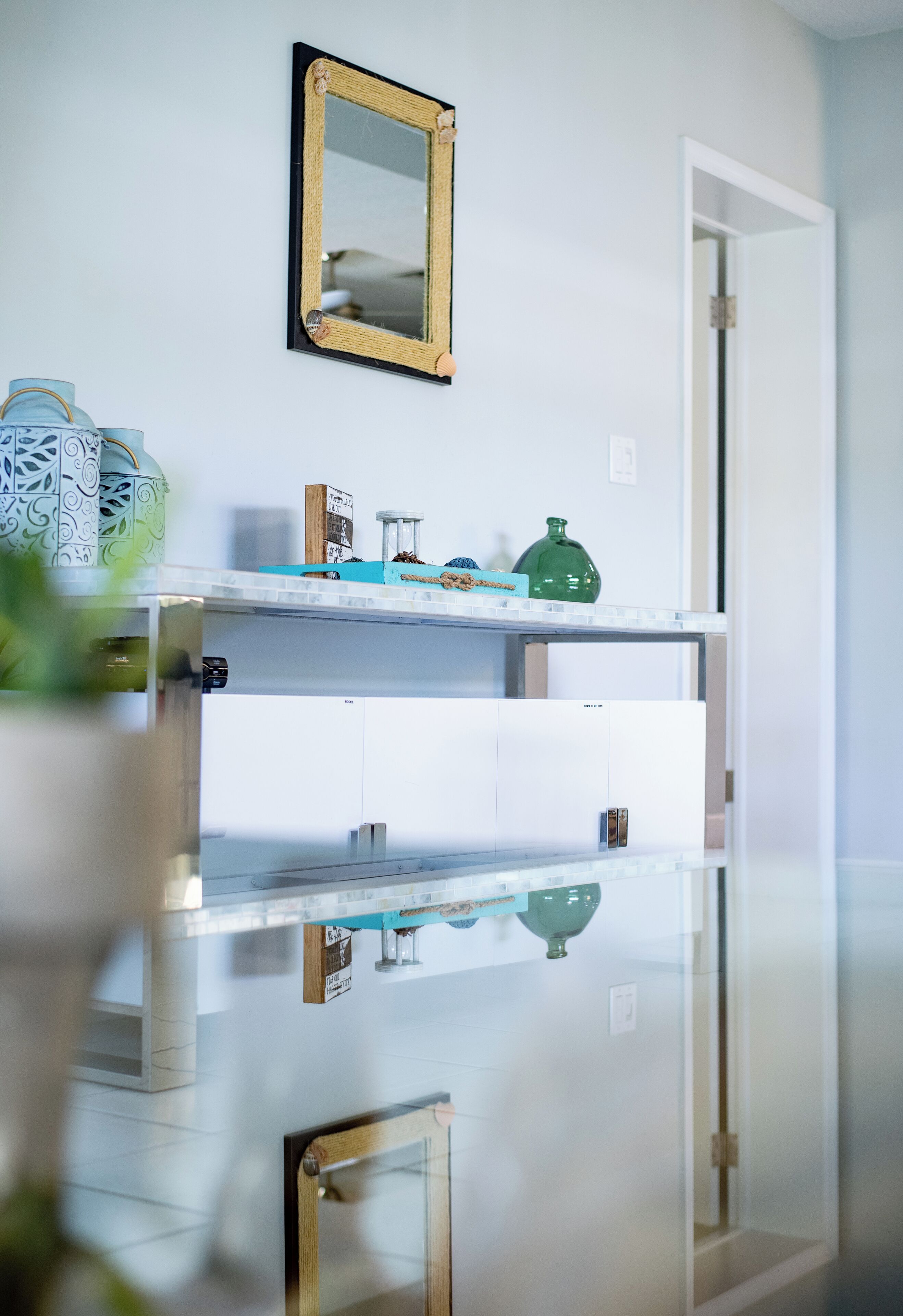 Une salle de bain avec une douche à parois de verre, un meuble-lavabo blanc avec un miroir et des objets décoratifs disposés sur les étagères.