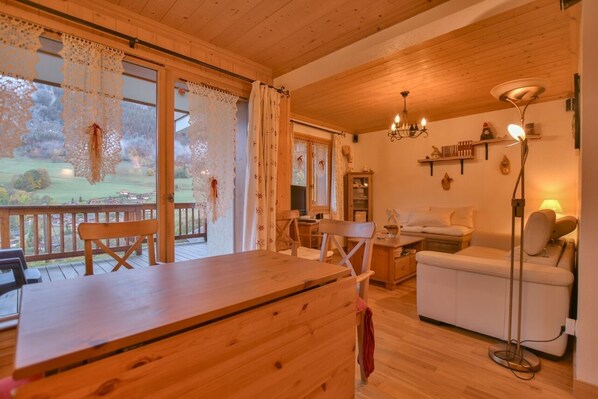L’intérieur d’un chalet chaleureux, avec une table à manger en bois, un canapé et un lustre.