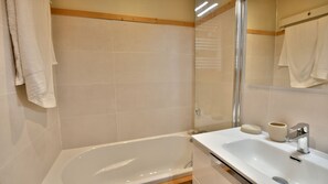 A bathroom with a bathtub, a sink, and a mirror.