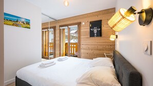 Une chambre moderne avec un grand lit, des murs recouverts de panneaux en bois et un balcon offrant une vue agréable.