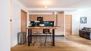 Une cuisine moderne avec des meubles en bois, un plan de travail noir et deux tabourets.