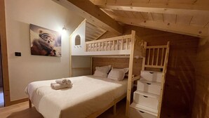 Une chambre mansardée chaleureuse, avec un lit superposé, un lit bien fait et un tableau accroché au mur.