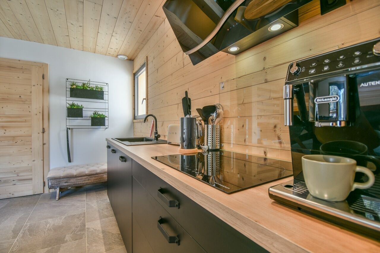 A modern kitchen with wooden cabinetry, a built-in stove, and a coffee machine.