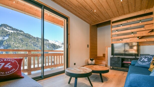 Un salon moderne doté d’une grande fenêtre, d’un plafond en bois et d’un téléviseur.