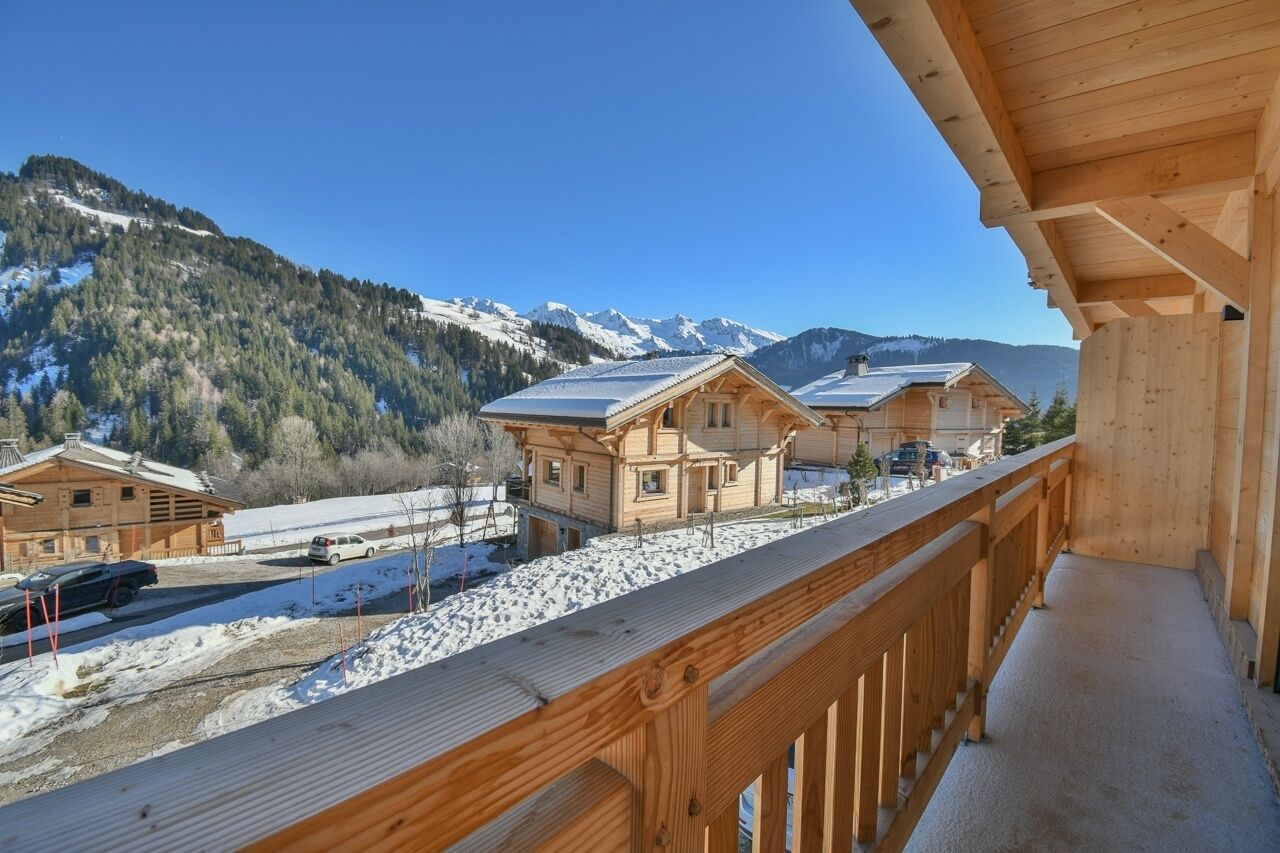 Una baita di legno con un balcone che si affaccia su un paesaggio montano innevato.