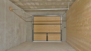 Un garage avec une porte en bois fermée, des murs en béton et un plafond en métal.