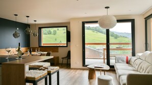 Una sala de estar moderna con un ventanal grande, un comedor con mesa de madera y un sofá.