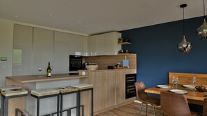 Una cocina moderna con una isla central, taburetes de bar y una mesa de comedor para cuatro.