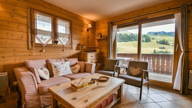 A cozy wooden cabin interior with a sofa, a table, and a chair.