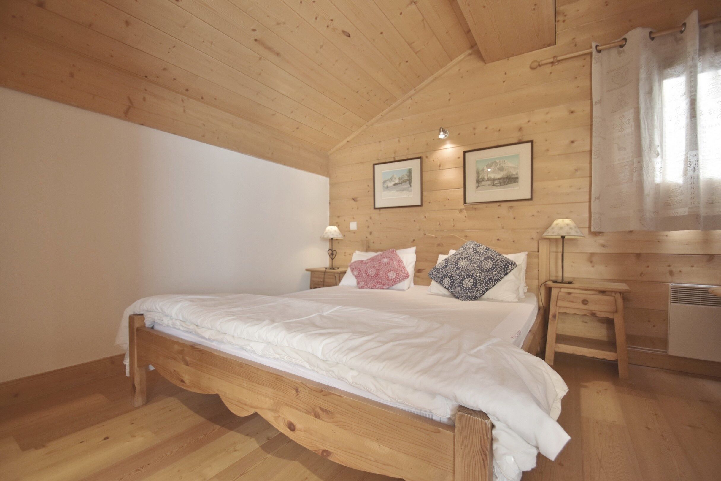 Ein Schlafzimmer mit Holzwandverkleidung, einem Einzelbett, zwei Nachttischen und zwei Wandleuchten.
