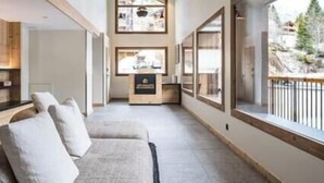 Un interior moderno con un sofá, estanterías de madera y vistas amplias a través de grandes ventanales.