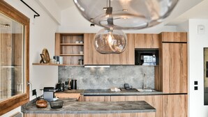 Una cocina moderna con armarios de madera, encimera de mármol y una lámpara colgante.
