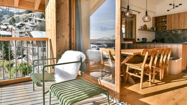 Un interior moderno con madera, balcón, comedor y cocina.