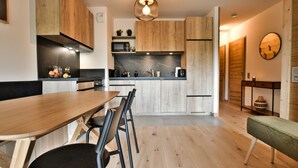 Ett modernt kök med träskåp, en bänkskiva i marmor och en matplats med ett träbord och stolar.