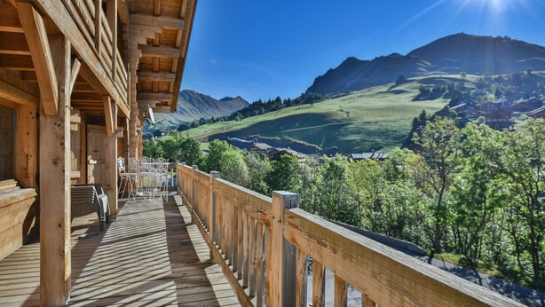 Un balcon en bois offrant une vue sur une vallée et des montagnes.