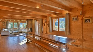L’intérieur d’un chalet en bois comprend une grande table à manger, un canapé et une cheminée.