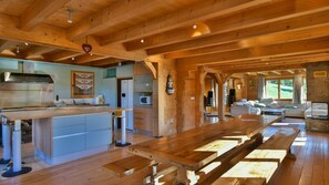 Una cocina amplia con una isla de madera, un comedor con bancos y una sala de estar con chimenea de piedra.