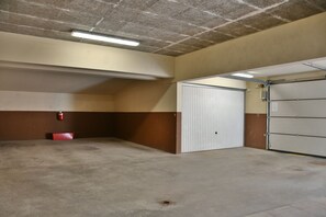 A parking garage with concrete floors, a fire extinguisher, and a closed garage door.