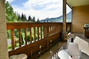 A balcony with a wooden railing overlooking a mountainous landscape.