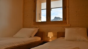 A room with two beds, a window, and a nightstand with a lamp.