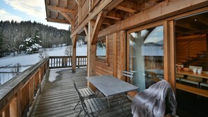 A wooden deck with a table and chairs, overlooking a snowy landscape.