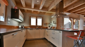 A modern kitchen with wooden beams, white cabinets, and a black countertop.