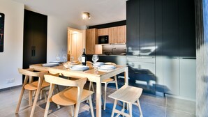 Una cocina moderna con armarios de madera, microondas integrado y un comedor con mesa y sillas de madera.