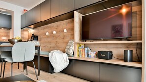 A modern kitchen with a built-in TV, wooden cabinetry, and a dining area with a table and chairs.