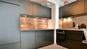 A modern kitchen with dark cabinetry, a stainless steel sink, and a Bosch oven.