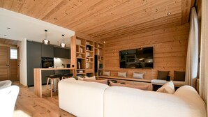 L’intérieur d’une maison en rondins moderne, avec un espace de vie chaleureux, une cuisine et un coin repas.