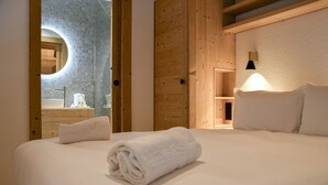 Une chambre d’hôtel avec un grand lit, une porte en bois et une lucarne circulaire.