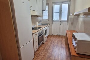 A compact kitchen with a washing machine, oven, and microwave.