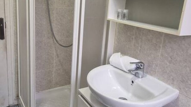 A bathroom with a shower, a sink, and a shelf with toiletries. - 135A1 Charming Apartment in Gijón by R2R (Gijón)