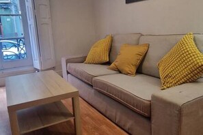 A living room with a sofa, a wooden coffee table, and yellow cushions.