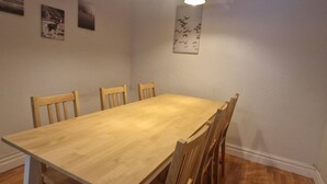 Un espace repas comprenant une table et des chaises en bois, un luminaire suspendu et des œuvres d’art murales.