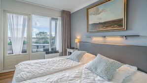 Ένα υπνοδωμάτιο με ένα κρεβάτι, έναν πίνακα, ένα κομοδίνο, ένα φωτιστικό και θέα από ένα παράθυρο.