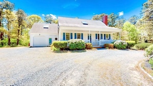 A two-story house with a covered porch and a garage. - Stevie, The Cape Farmhouse (Chatham)