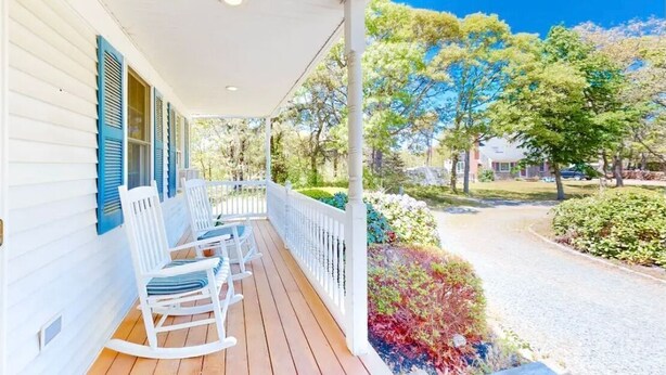 A porch with white rocking chairs and a white fence. - Stevie, The Cape Farmhouse (Chatham)