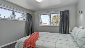 Une chambre à coucher avec un lit, deux fenêtres, un luminaire au plafond et une vue sur l’extérieur.