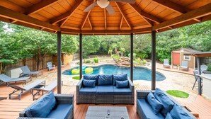 A covered outdoor patio with a pool, seating area, and a view of a backyard. - Pool, Games & BBQ Luxury Texas Home 4 bedroom (San Antonio)