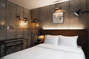 Een slaapkamer met een bed, een bureau, twee krukken, een nachtkastje, een lamp en een aan de muur hangend schilderij.