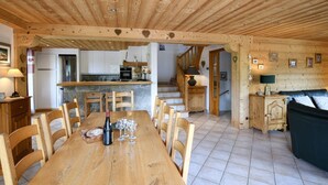 A wooden interior with a dining area, kitchen, and staircase. - Chalet Anou - proche pistes de ski (Le Grand Bornand)