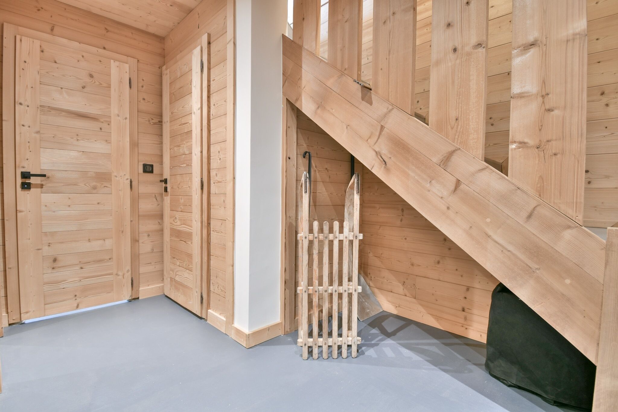 Interior de madeira com escada e uma porta.