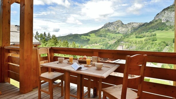 A wooden deck with a table and chairs overlooking a mountainous landscape. - Refuge les Echelles E4 (Le Grand Bornand)