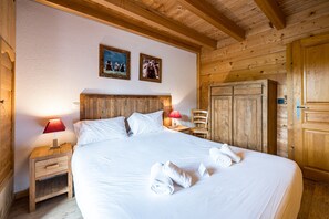 Un dormitorio tipo cabaña de madera con una cama grande, dos lámparas de noche, un armario de madera y dos cuadros en la pared.